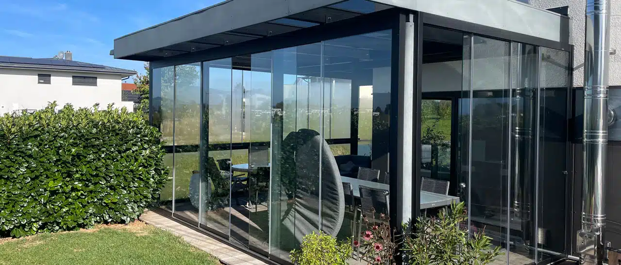 Nachgerüsteter Sommergarten in OÖ: Terrassenüberdachung aus Stahl wurde mit Glasschiebewände wind- & sturmfest gemacht.