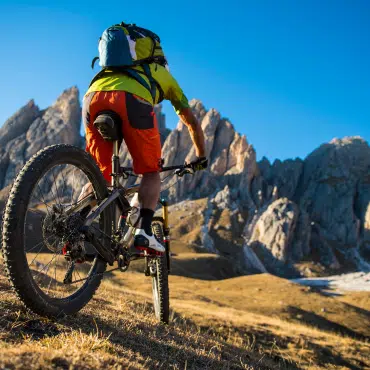 Mountainbiker erklimmt Berg – symbolisiert Teamgeist & Abenteuer im Betriebsurlaub von Fenster Schmidinger.