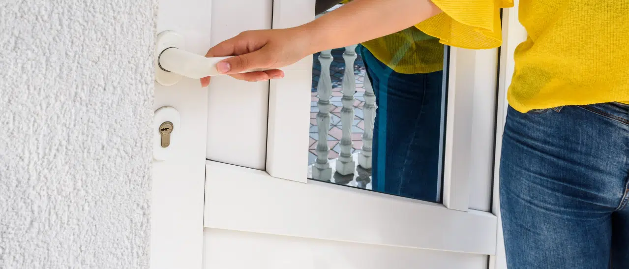 Eine Frau öffnet eine Kunststoff-Nebeneingangstür, was die praktische Erfahrung mit Kunststoff-Nebeneingangstüren zeigt.