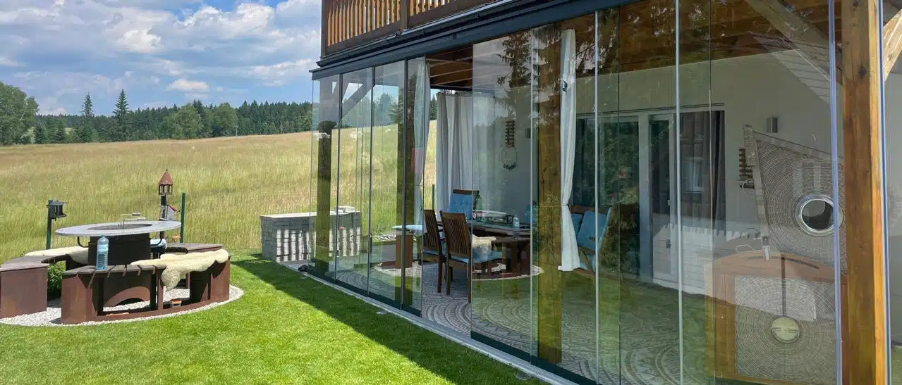 Glasschiebewand in Holzrahmen auf Terrasse am Lipno-Stausee installiert, schützt vor Wind und Regen.