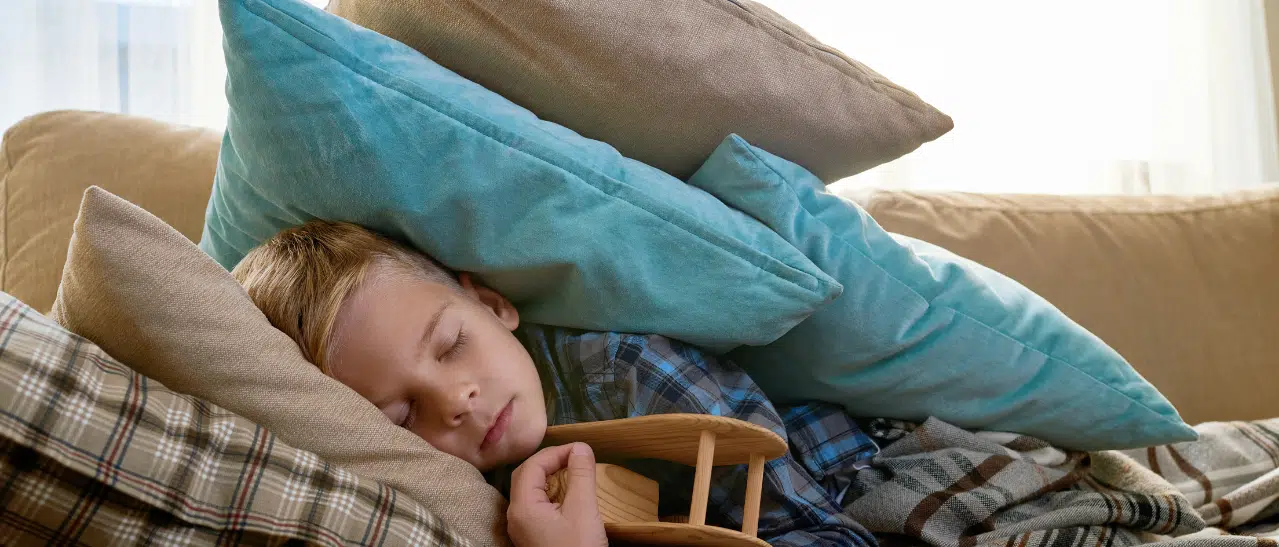 Kind schläft friedlich auf Couch, dank schalldämmender Fenster im Wohnzimmer: Ruhe & Entspannung pur.