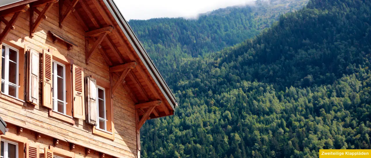 Zweiteiliger Klappladen aus Holz an rustikalem Einfamilienhaus in Österreich im geöffneten Zustand.